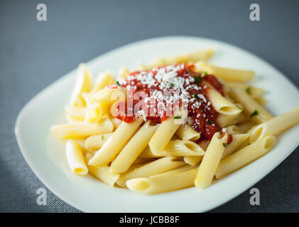 Portion traditionelle gekochte Penne Rigate Nudeln garniert mit einer würzigen Tomatensauce, garniert mit geriebenem Parmesan Stockfoto