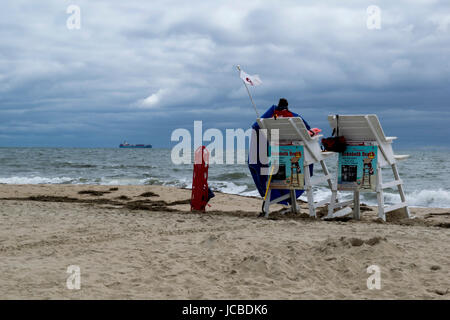 Strand Bademeister in Rehoboth Beach, DE, während stürmischer Tag mit Schiff in Ferne. Stockfoto