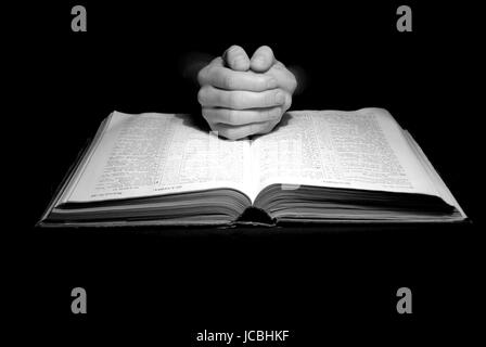 A mans Hände im Gebet über eine Bibel Stockfoto