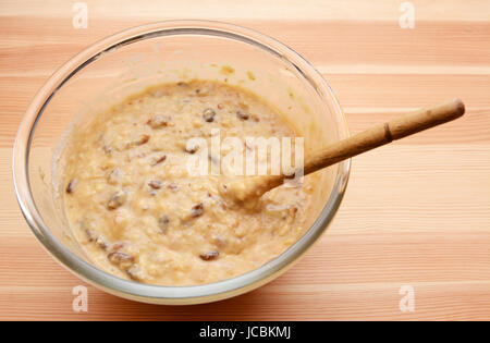 Bananen Brot in eine Glasschüssel mit einem hölzernen Löffel Teig vorbereitet Stockfoto