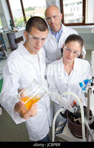 zwei Schüler durchführen Experiment in einem Labor unter Aufsicht der Lehrer Stockfoto