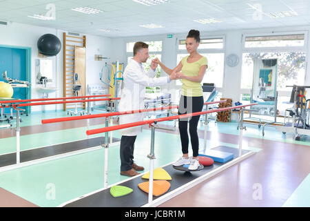 schöne Frau auf Laufband Rehabilitation geholfen durch Therapeuten Stockfoto