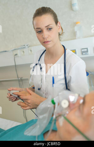 schöne junge Ärztin überprüft Patienten Blutdruck Stockfoto