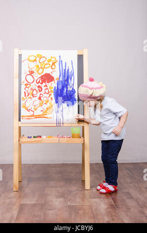 Drei-jährigen Mädchen spielen in der Künstler. Mädchen stützt sich auf die Staffelei-Lacke Stockfoto