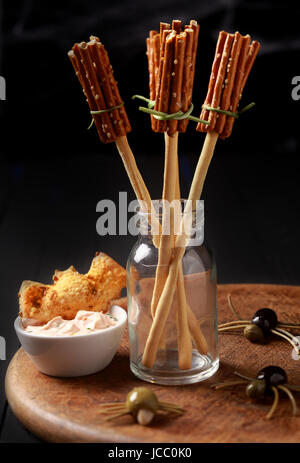 Kreative Halloween snacks und Vorspeisen mit Hexen Besen aus Brot-Sticks und Brezeln mit gruselige Spinnen von Oliven und Spaghetti auf einem Tisch in einem Halloween-Feier Stockfoto