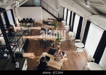 Hübschen weiblichen Arbeitnehmer erfreuen sich ihre Arbeit. Zwei Geschäftsfrauen in einem Café sitzen, ist eine in die Kamera schaut. Stockfoto