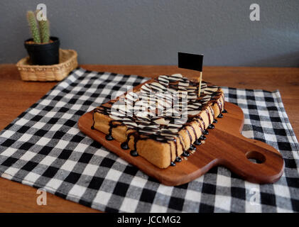 Toast belegt mit in Scheiben geschnittenen Bananen, Nüssen, Schokolade und Karamell-Sirup Stockfoto