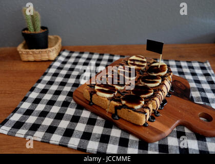 Toast belegt mit in Scheiben geschnittenen Bananen, Nüssen, Schokolade und Karamell-Sirup Stockfoto