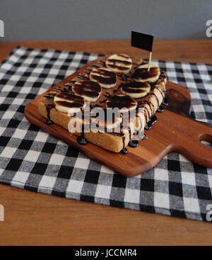Toast belegt mit in Scheiben geschnittenen Bananen, Nüssen, Schokolade und Karamell-Sirup Stockfoto