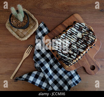 Toast belegt mit in Scheiben geschnittenen Bananen, Nüssen, Schokolade und Karamell-Sirup Stockfoto