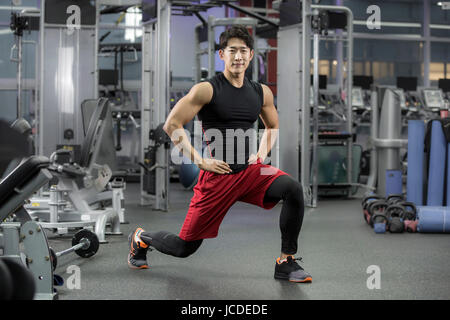 Junger Mann stehend und stretching Beine im Health club Stockfoto