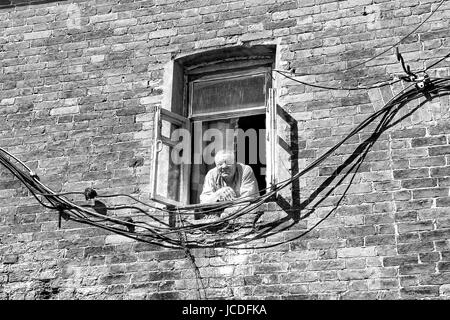 VALAAM, Russland - 15. August 2015, Blick auf einen alten Mann, der Blick aus einem Fenster ein Backsteingebäude, am 15. August 2015 in VALAAM, Russland Stockfoto