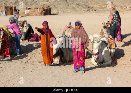 HURGHADA, Ägypten - 24. April 2015: Die junge Mädchen-Nomadenlager von Beduinen-Dorf in der Wüste Sahara mit ihrem Kamel schreien lädt Touristen, Ägypten, HURGHA Stockfoto