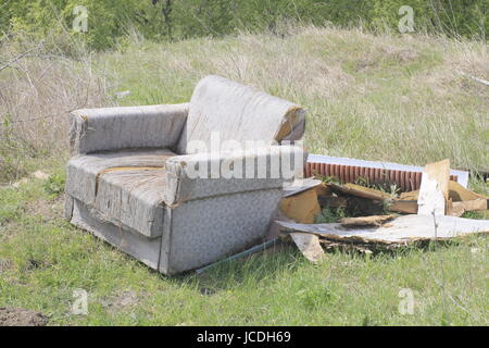 Ein Bild oder ein Bild zeigt einen alten Sitz oder Stuhl entsorgt Müll in einem Feld mit anderem Müll. Stockfoto