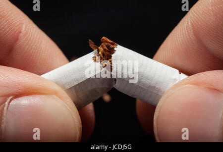 Nahaufnahme der Hand brechen Zigarette auf schwarzem Hintergrund Stockfoto