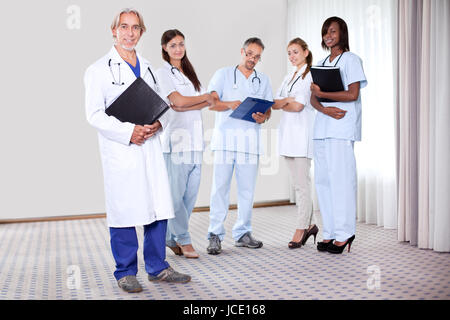 Team von medizinischen Fachleuten unter der Leitung von Reifen glücklich Arzt Betriebskartei Blick in die Kamera - Lächeln auf den Lippen. Stockfoto