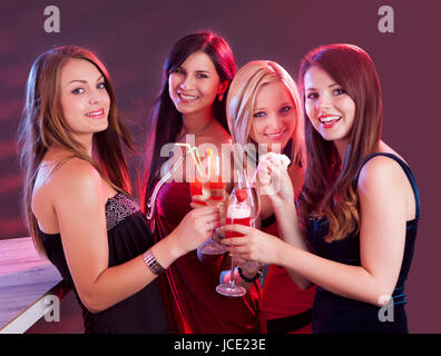 Gruppe von vier glückliche schöne junge Freundinnen feiern in einem Nachtclub mit Gläser cocktail in der Hand Stockfoto