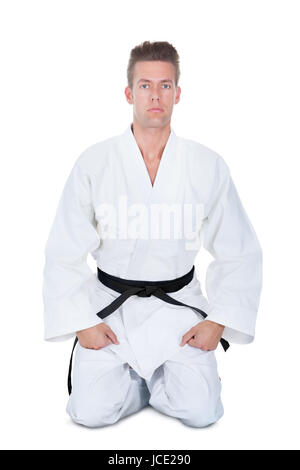 Junger Mann im Kimono kniend Over White Background Stockfoto
