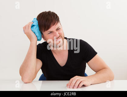 Nüchterne junge hübscher Kerl bekam Kopfschmerzen und Eisbeutel anwenden Stockfoto