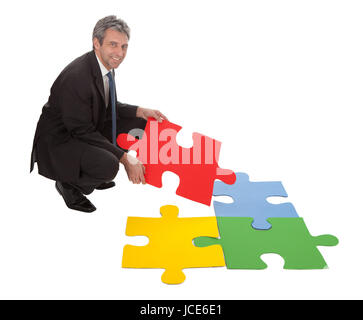 Leitenden Geschäftsmann Montage eine Puzzle. Isoliert in weiss Stockfoto