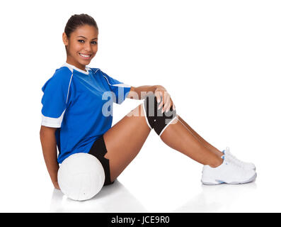 Fröhliches junges Mädchen sitzen mit Volleyball. Isolated On White Stockfoto