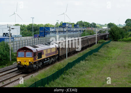 Class 66-Diesellok ziehen einen Güterzug vorbei an Tesco Lager, DIRFT, Northamptonshire, UK Stockfoto