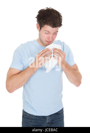 Junger Mann Niesen im Gewebe isoliert auf weißem Hintergrund Stockfoto