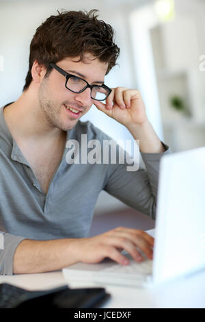 Junger Mann elearning von zu Hause aus mit Laptop sitzen ...