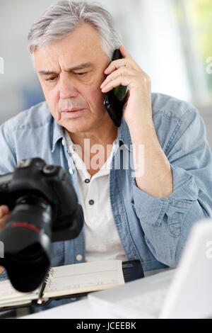 Fotograf im Büro am Telefon im Gespräch mit Kunden Stockfoto