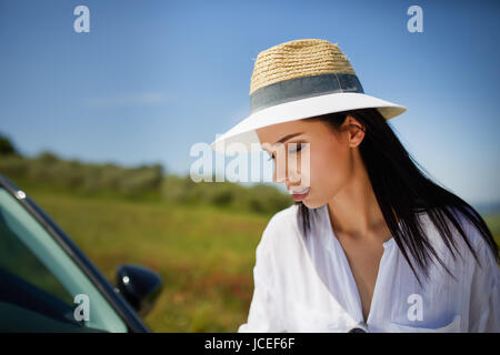 Ein Tourist mit einer Karte am Auto prüft die Route zum Ziel Stockfoto