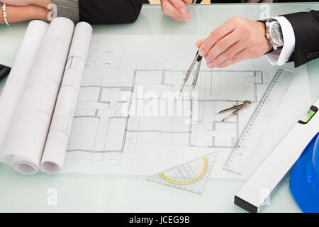 Draufsicht eines männlichen und weiblichen Architekten diskutieren eine Reihe von Plänen, die auf einem Tisch ausgebreitet beschnitten Stockfoto