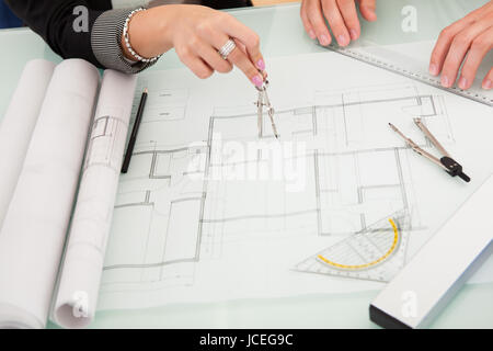 Draufsicht eines männlichen und weiblichen Architekten diskutieren eine Reihe von Plänen, die auf einem Tisch ausgebreitet beschnitten Stockfoto