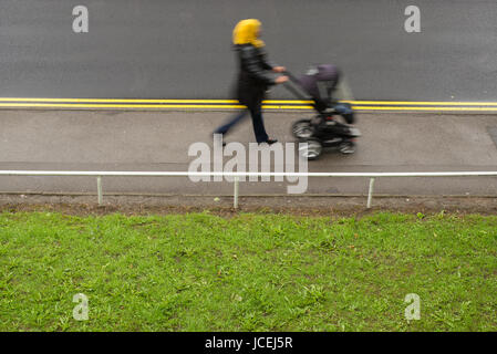 Doppelzimmer mit gelben Linien für das Parken Beschränkung der städtischen Straße mit Gehweg und Grünfläche, die mit dem Übertragen von Mutter und Kind im Kinderwagen, Sheffield, Großbritannien Stockfoto