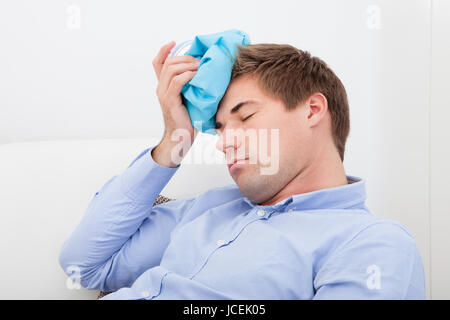 Junger Mann leiden mit Kopfschmerzen anwenden von Icepack Stockfoto