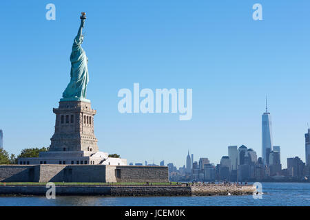 Statue von Liberty Island und New York City Skyline an einem sonnigen Tag, blauer Himmel Stockfoto