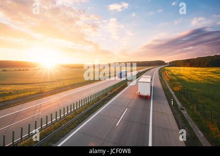 Wunderbaren Sonnenaufgang auf der Autobahn mitten in der Natur. Verkehrsmittel und Autos Thema. Stockfoto