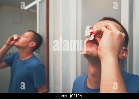 Mann mit Nasenbluten im Badezimmer. Für Themen wie Krankheit, Unfall oder Gewalt. Stockfoto