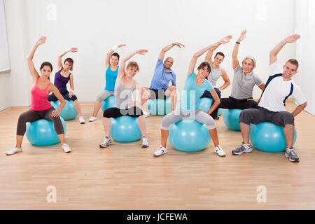 Große Gruppe von verschiedenen Menschen in einer Pilates-Klasse-Turnen in der Turnhalle üben Balance und Kontrolle Stockfoto