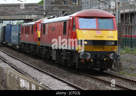 Zwei rote e-Loks von DB Cargo mit einem Containerzug durch Carnforth, Lancashire auf der West Coast Main Line betrieben. Stockfoto