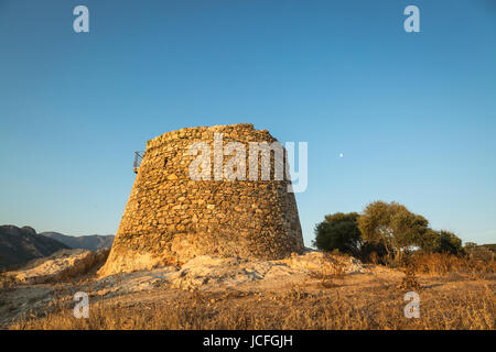 Alten Genueser Stein Turm am Lozari in der Balagne Region Korsikas, beleuchtet von frühen Morgensonne mit dem Mond hinter in der Ferne Stockfoto