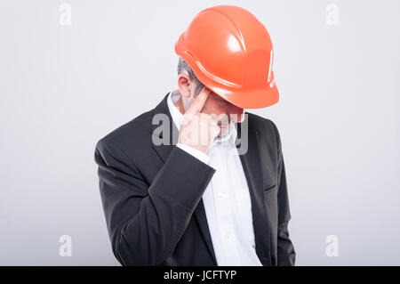 Vorarbeiter tragen Helm machen denken Geste schaut auf grauem Hintergrund Stockfoto