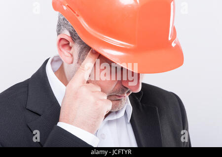 Nahaufnahme des Vorarbeiters tragen Helm machen denken Geste schaut auf grauem Hintergrund Stockfoto