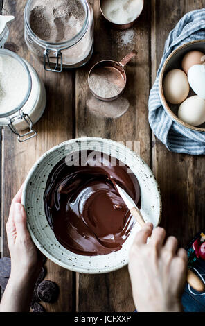 Geschmolzene Schokolade Zuckerguss wird gerührt, in eine Rührschüssel geben Stockfoto