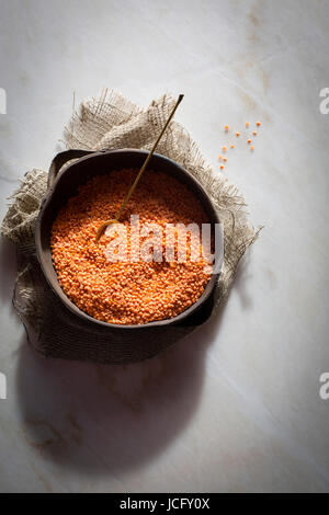 Masoor dal / Rot/Orange Linsen in einer Keramikschale auf eine Murmel Tabelle Draufsicht Stockfoto