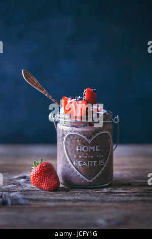 Chocokate Chia Pudding mit Erdbeeren, Kokosflocken und Kakaonibs gekrönt Stockfoto