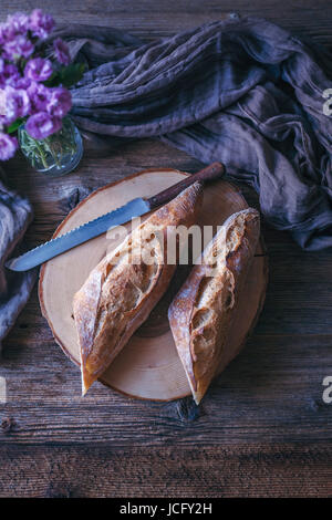 Sauerteig-Baguette in Scheiben geschnitten, in der Mitte auf einem rustikalen Holztisch Stockfoto