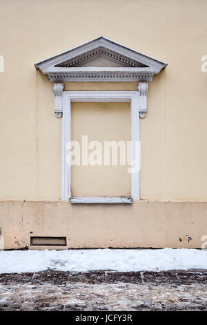 Gelbe Wand mit eingemauerten Fenster im winter Stockfoto