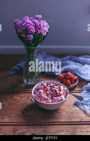 Erdbeer-Banane Eis in eine Schüssel geben, garniert mit Goji-Beeren und Kakaonibs Stockfoto