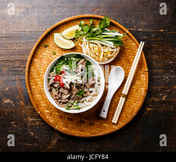 Pho Bo-vietnamesische Suppe mit Rindfleisch auf Bambus Tablett auf hölzernen Hintergrund Stockfoto