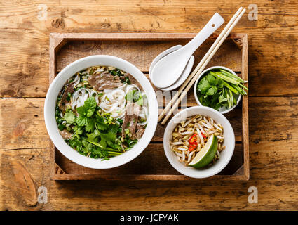 Pho Bo-vietnamesische Suppe mit Rindfleisch in Holztablett auf hölzernen Hintergrund Stockfoto